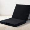 Matelas pliant noir compact sur tapis.